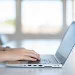 a close up of a person typing on a laptop