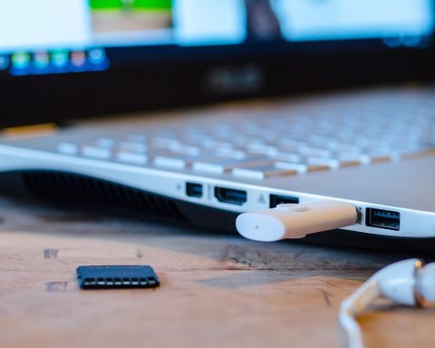 Draadloze koptelefoon liggend op een bureau naast een laptop