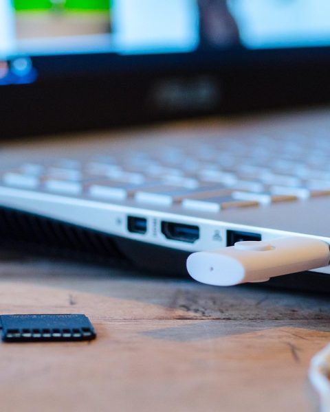 Draadloze koptelefoon liggend op een bureau naast een laptop