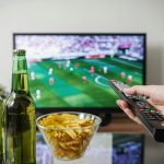 Persoon ontspannen op de bank kijkt naar een streamingdienst op televisie