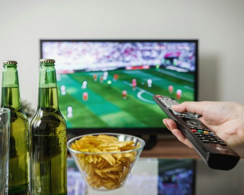 Persoon ontspannen op de bank kijkt naar een streamingdienst op televisie
