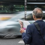 Persoon die zowel een papieren krant als een tablet vasthoudt, als symbool voor de overgang van analoge naar digitale media