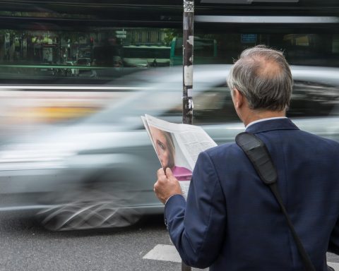 Persoon die zowel een papieren krant als een tablet vasthoudt, als symbool voor de overgang van analoge naar digitale media