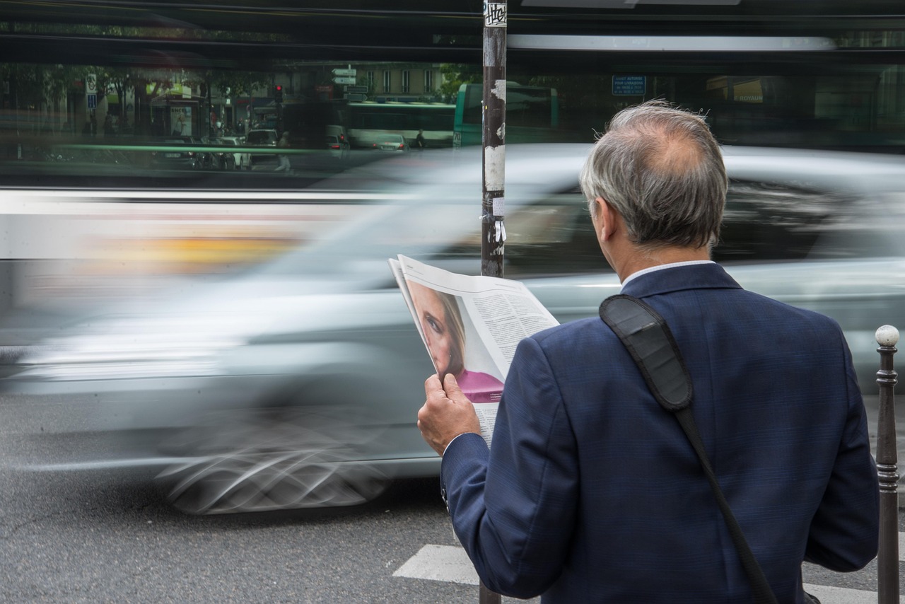 Persoon die zowel een papieren krant als een tablet vasthoudt, als symbool voor de overgang van analoge naar digitale media