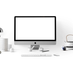 Medewerker aan bureau met meerdere schermen vol open applicaties, zichtbaar overweldigd