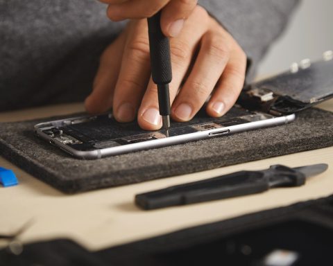 Een smartphone die wordt opengebroken voor reparatie, met schroeven en gereedschap op tafel