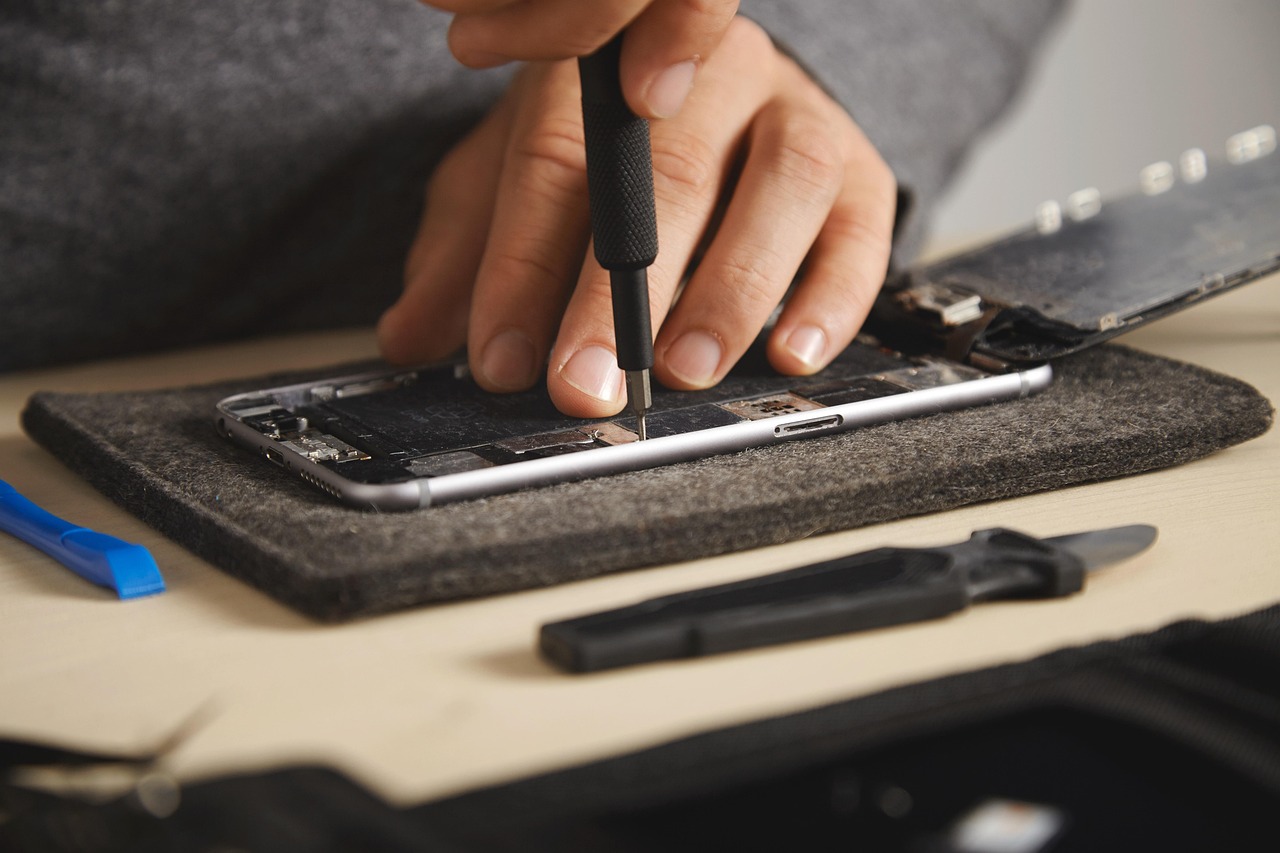 Een smartphone die wordt opengebroken voor reparatie, met schroeven en gereedschap op tafel