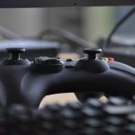 Een persoon die 's avonds een videogame speelt achter een monitor met kleurrijke verlichting