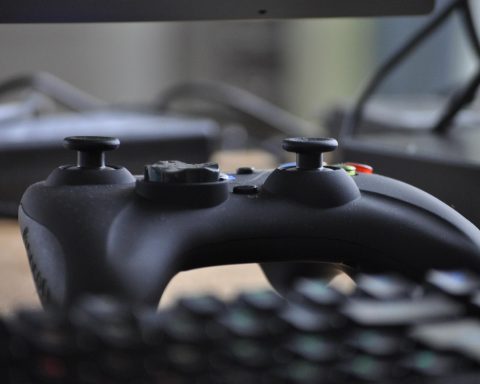 Een persoon die 's avonds een videogame speelt achter een monitor met kleurrijke verlichting