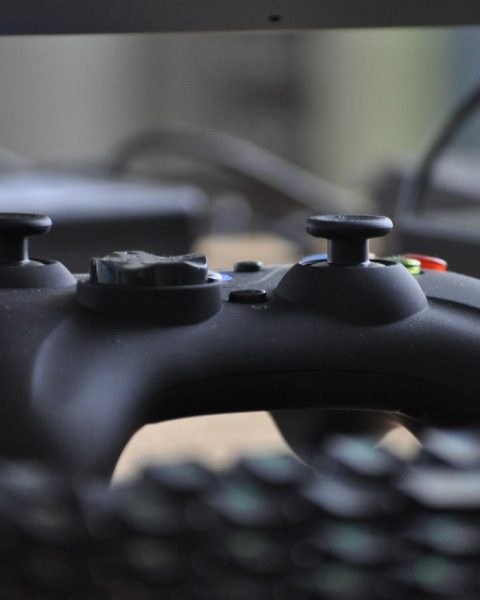 Een persoon die 's avonds een videogame speelt achter een monitor met kleurrijke verlichting