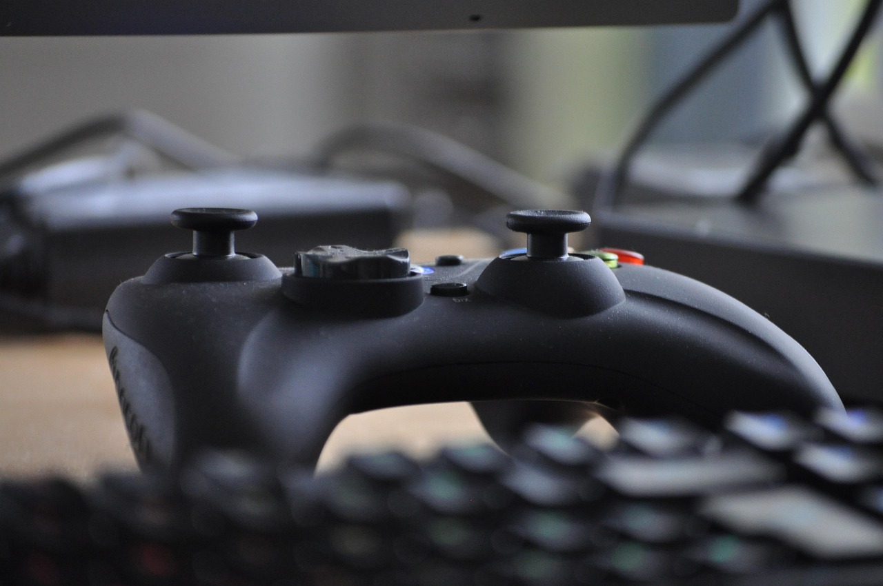 Een persoon die 's avonds een videogame speelt achter een monitor met kleurrijke verlichting