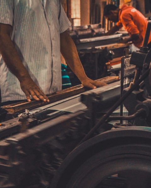 man in white and black stripe shirt standing in front of black and gray machine