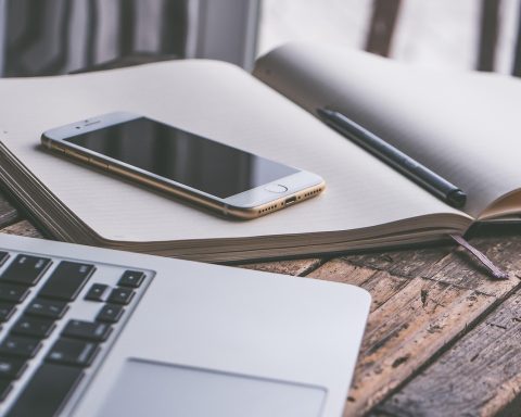 Een laptop en smartphone naast elkaar op een bureau, symbool voor het schakelen tussen Windows en Android
