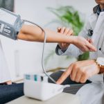 Een persoon meet zijn bloeddruk thuis met een bovenarmmonitor
