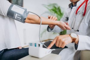 Een persoon meet zijn bloeddruk thuis met een bovenarmmonitor
