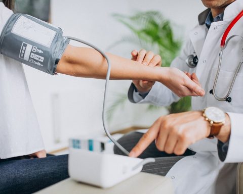 Een persoon meet zijn bloeddruk thuis met een bovenarmmonitor