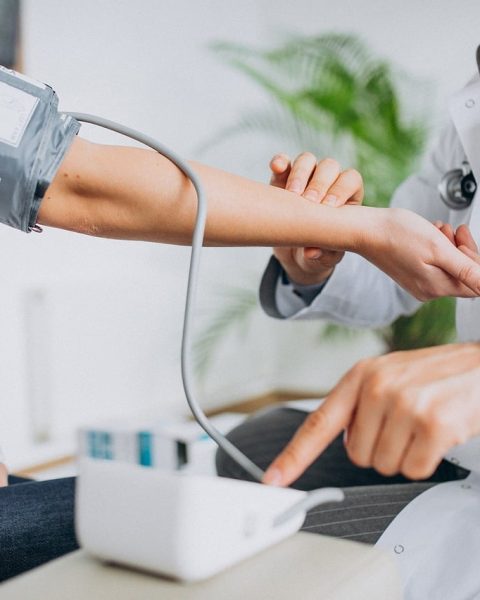 Een persoon meet zijn bloeddruk thuis met een bovenarmmonitor